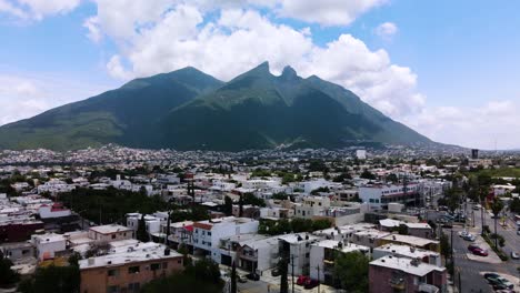 Amazing-view-of-a-mountain-in-the-background-while-drone-is-rising-through-the-streets-of-neighborhood-in-Monterrey,-Mexico