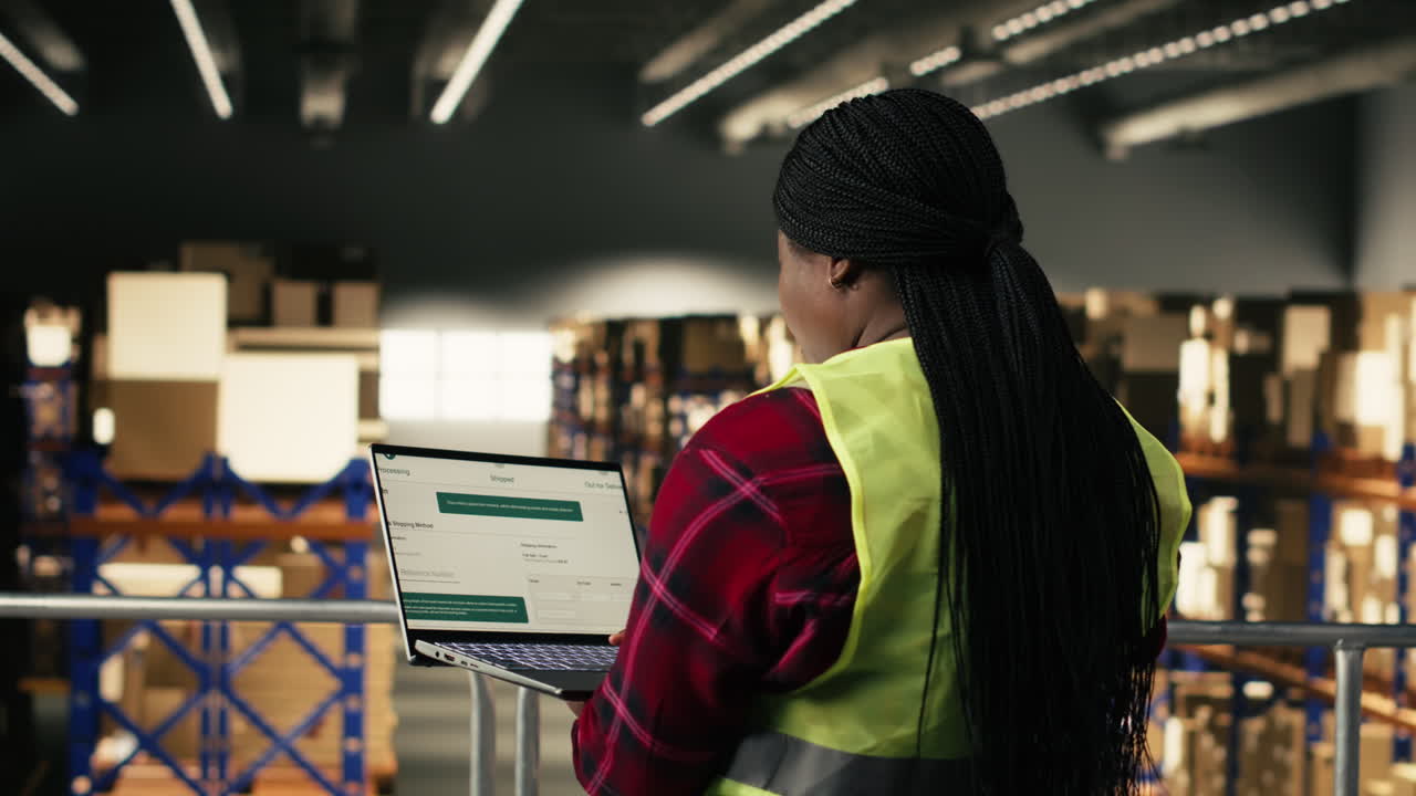 African American Woman Working on Laptop in Warehouse