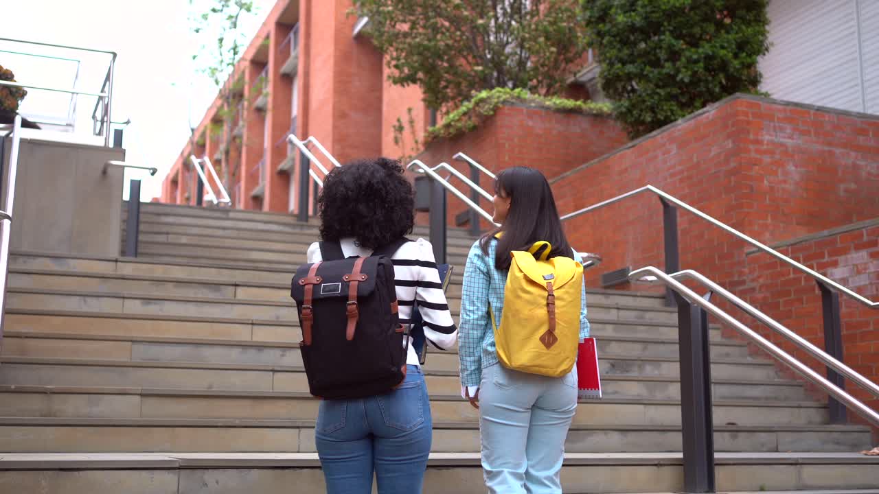 Two students climbing stairs with backpacks