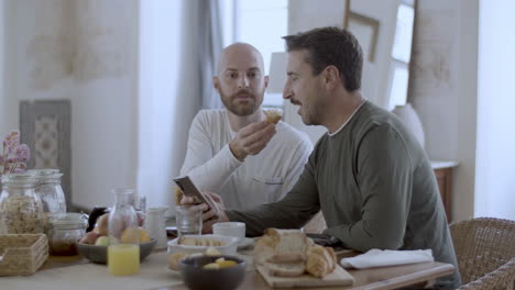 Handsome-gay-feeding-partner-with-bun-at-breakfast