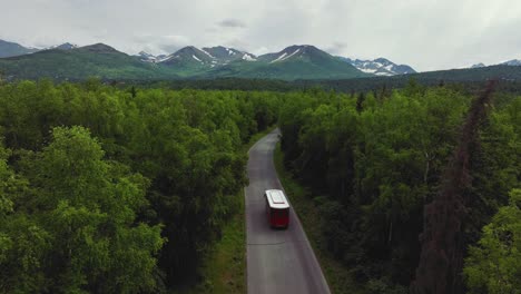 anchorage trolley tour bus traveling across the road with forest trees in anchorage, alaska