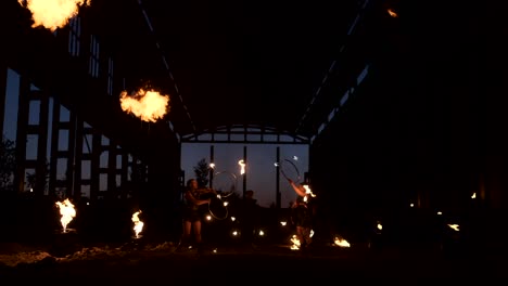 a group of people with fire and torches dancing at sunset in the hangar in slow motion. fire show