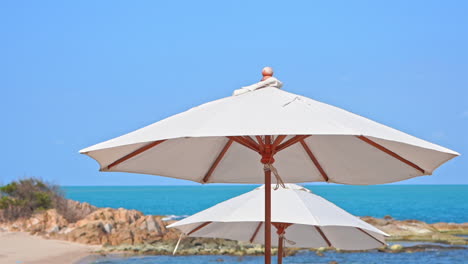 Close-up-of-parasols-on-light-summer-breeze-at-tropical-beach,-full-frame