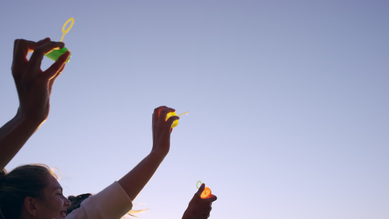 해가 지면 해변에서 거품을  ⁇ 는 여자 친구들이 느린 동작을 하고 있습니다.