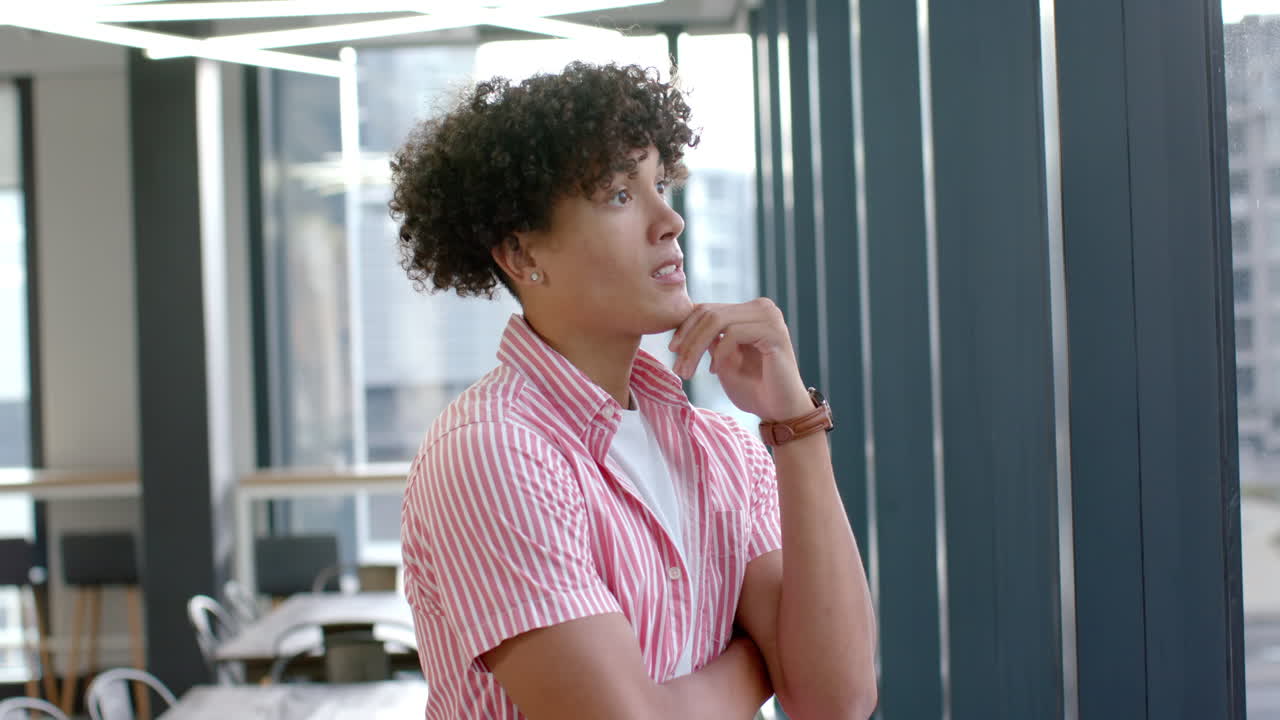Young man in striped shirt standing confidently in modern office setting