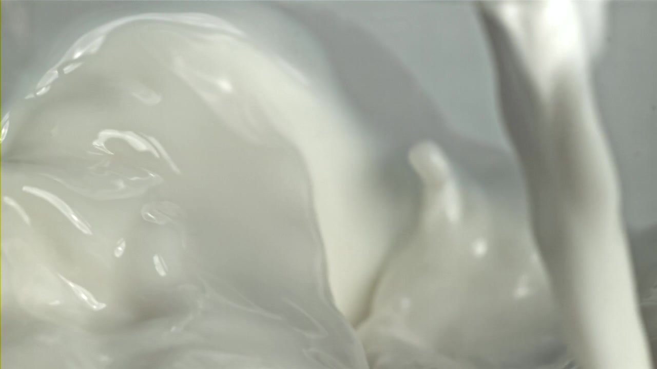 Liquido bianco cremoso che si versa e schizza al rallentatore
