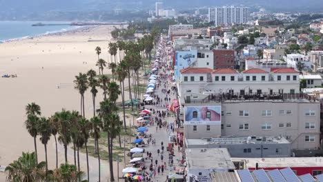 overlooking the famous venice beach boardwalk, crowded with people, aerial static view