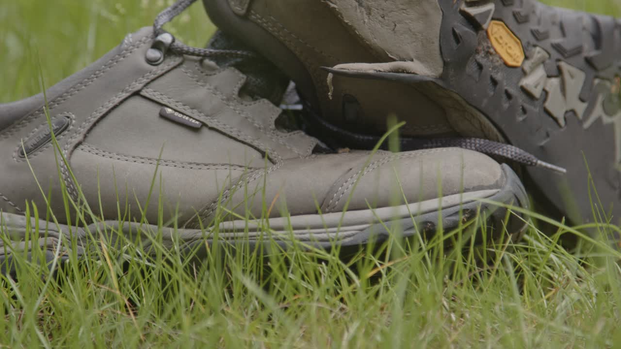 primer plano de zapatos de senderismo desechados que yacen en un campo de hierba