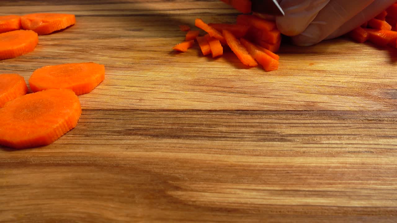 El cocinero corta zanahorias en una tabla de cortar