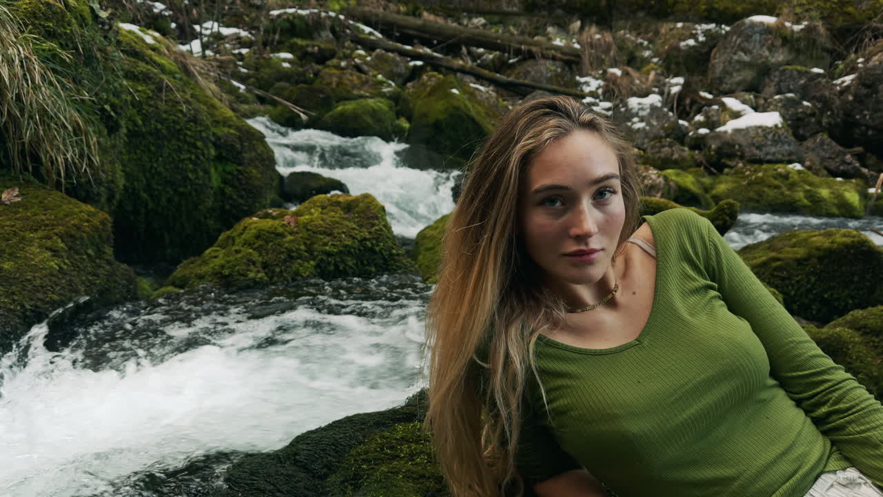 Woman relaxing by a mountain stream in winter