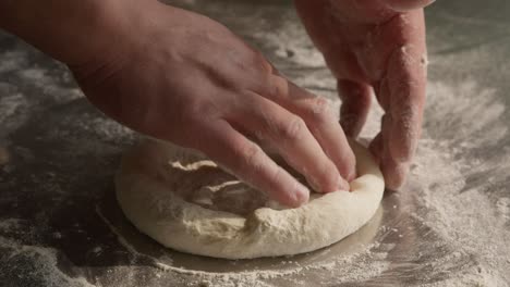 male hands kneads the dough in closeup with flour on table