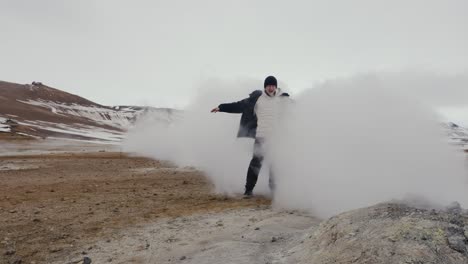 tourist stand behind steam vent and enjoy warm vapor at geothermal area