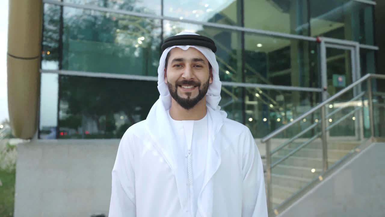 Kameraan katsova arabimies kandurassaan. Arabiemiraattien liikemies hymyilee katsoessaan eteenpäin, pukeutuneena Lähi-idän vaatteisiin.
