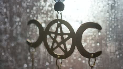 close-up of a moon pentagram decoration hanging in a screen window on a rainy day