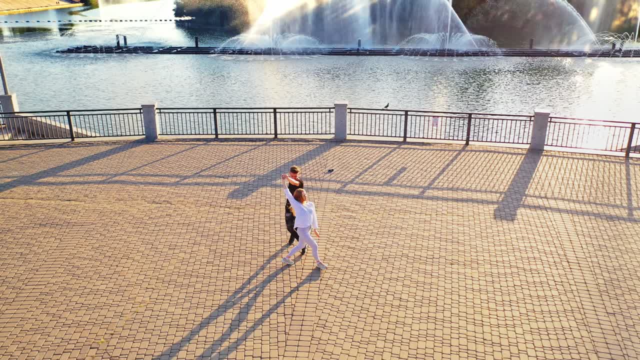 Happy teens dancing near river. Aerial view of carefree couple in love dancing near river