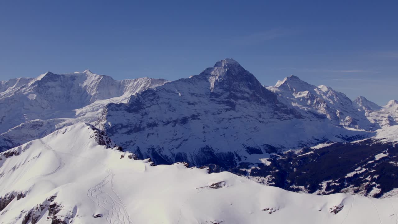 Riprese aeree con drone che vola sopra una cima montuosa innevata verso la parete nord dell'Eiger