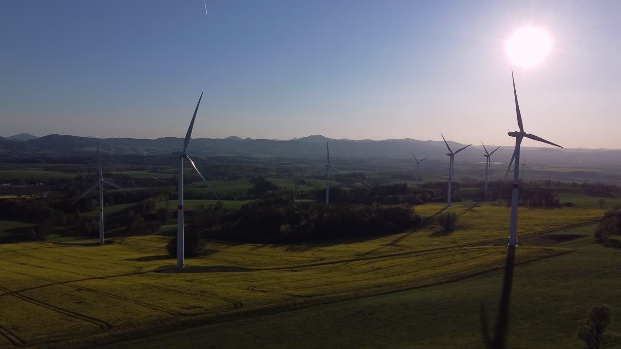 Drone view of windmills farm on meadow, spring colors before sunset, fly toward