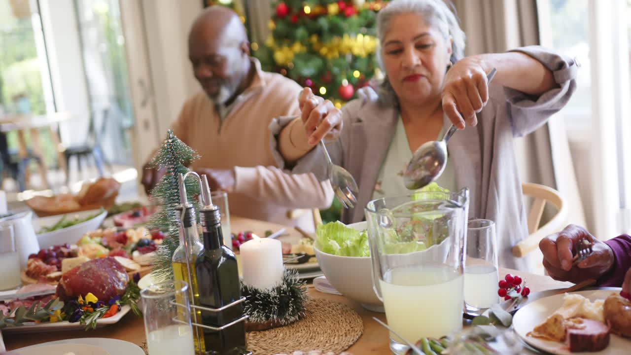amigos adultos felices y variados, hombres y mujeres, comiendo y sirviendo la cena de navidad, en cámara lenta.
