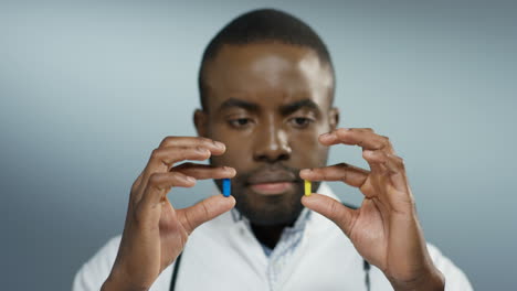 Close-Up-Of-The-Young-Doctor-Holding-Two-Pills-In-Hands-Yellow-And-Blue-And-Looking-At-Them