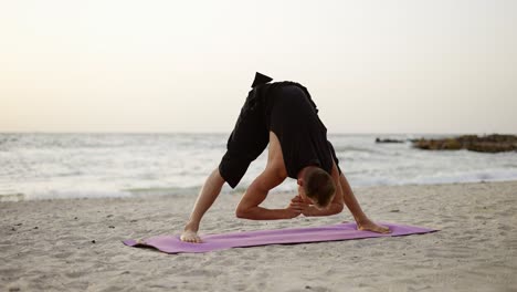 a young man practices yoga while standing on a sports mat at dawn. performing a specific exercise. body stretch. free time, rest