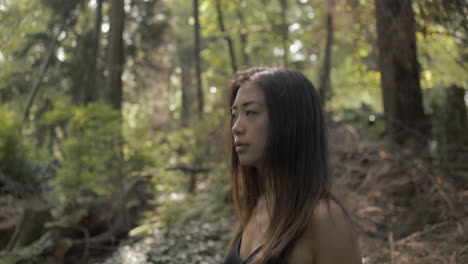 foto de perfil de primer plano medio de mujer asiática en negro explorando bosque soleado, variación, cámara lenta