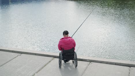 persona con discapacidad física que utiliza silla de ruedas para pescar en el muelle de pesca