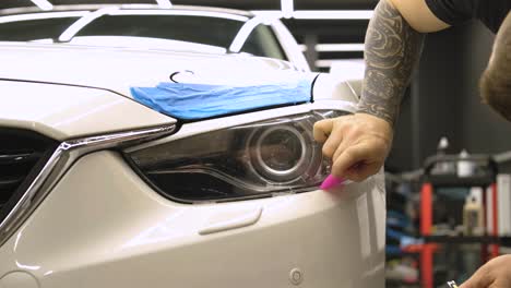 man covering car with vinyl polyurethane tape. films for the car. sticker protective film on the headlight of the car