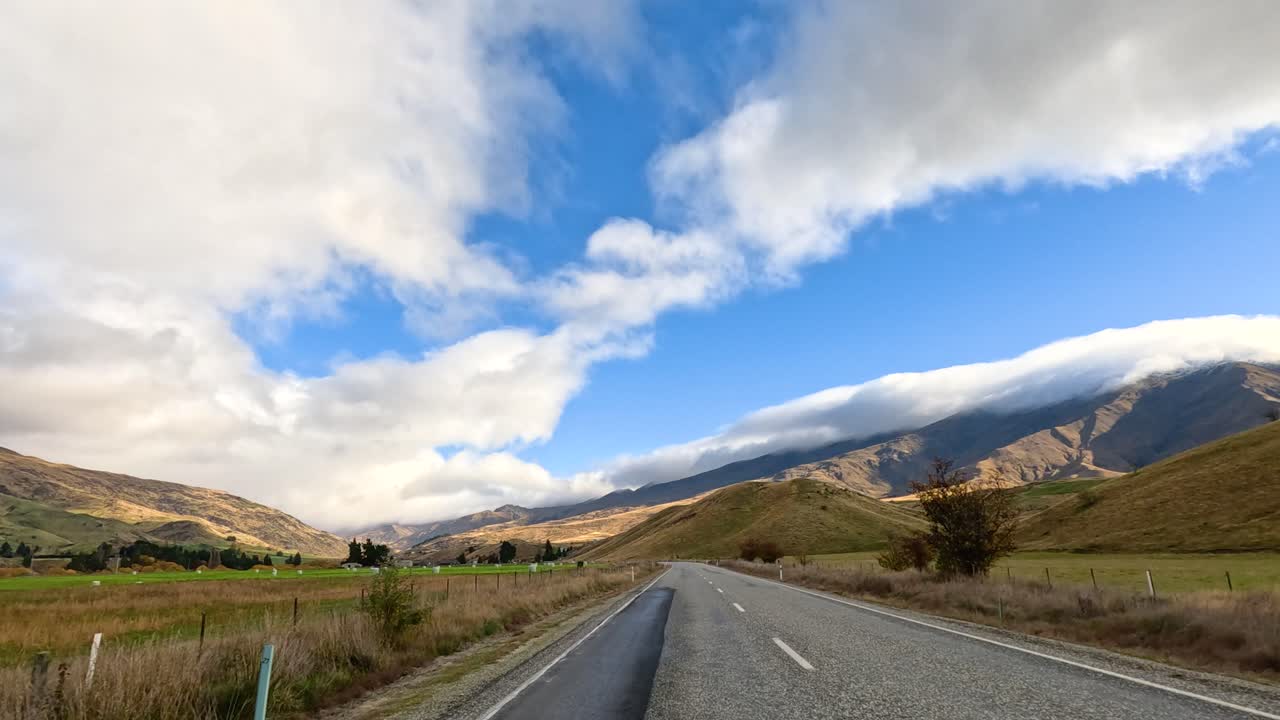 A picturesque drive through Wanaka, showcasing expansive skies, rolling hills, and open roads under dynamic lighting