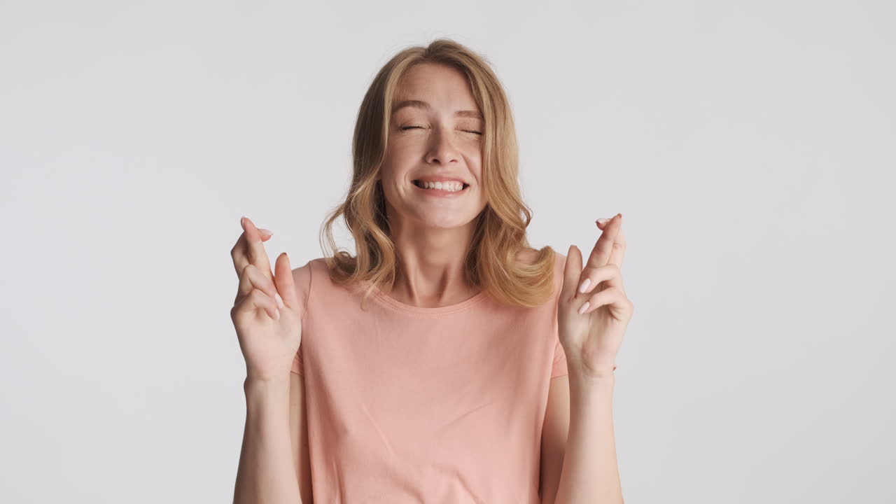 кавказская женщина с нетерпением скрещивает пальцы перед камерой.