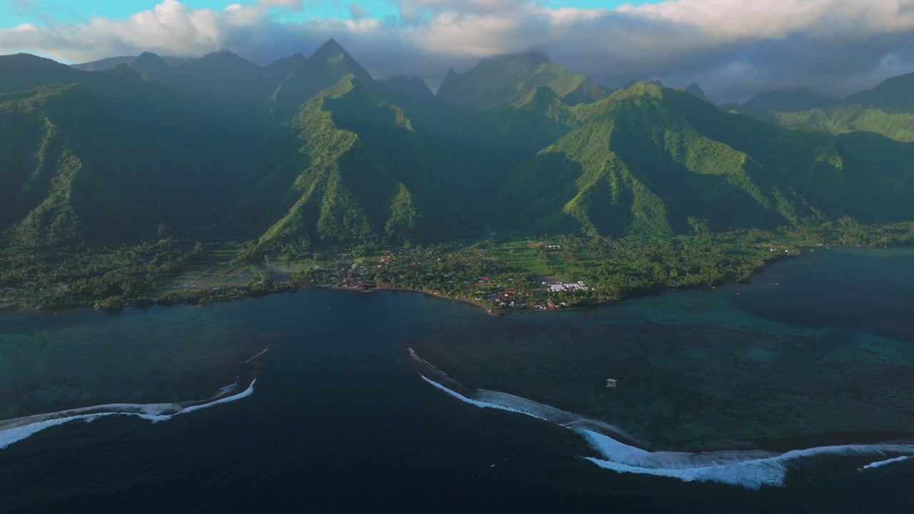 Tahiti lagoon landscape aerial drone harbor view French Polynesia Teahupo'o surf wave Passe Havea coral reef South Pacific Ocean island golden sun rays volcano peaks low clouds coastline upwards