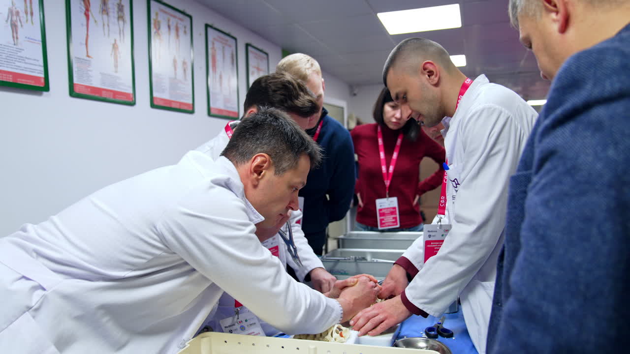 Students are practicing neurosurgery using modern tools. Man in white robe holds a spine dummy tightly.