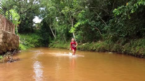 hispanic boy running down the river stream in paraguay