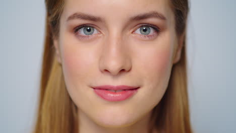 Closeup-pretty-girl-face-smiling-at-camera-on-grey-background.