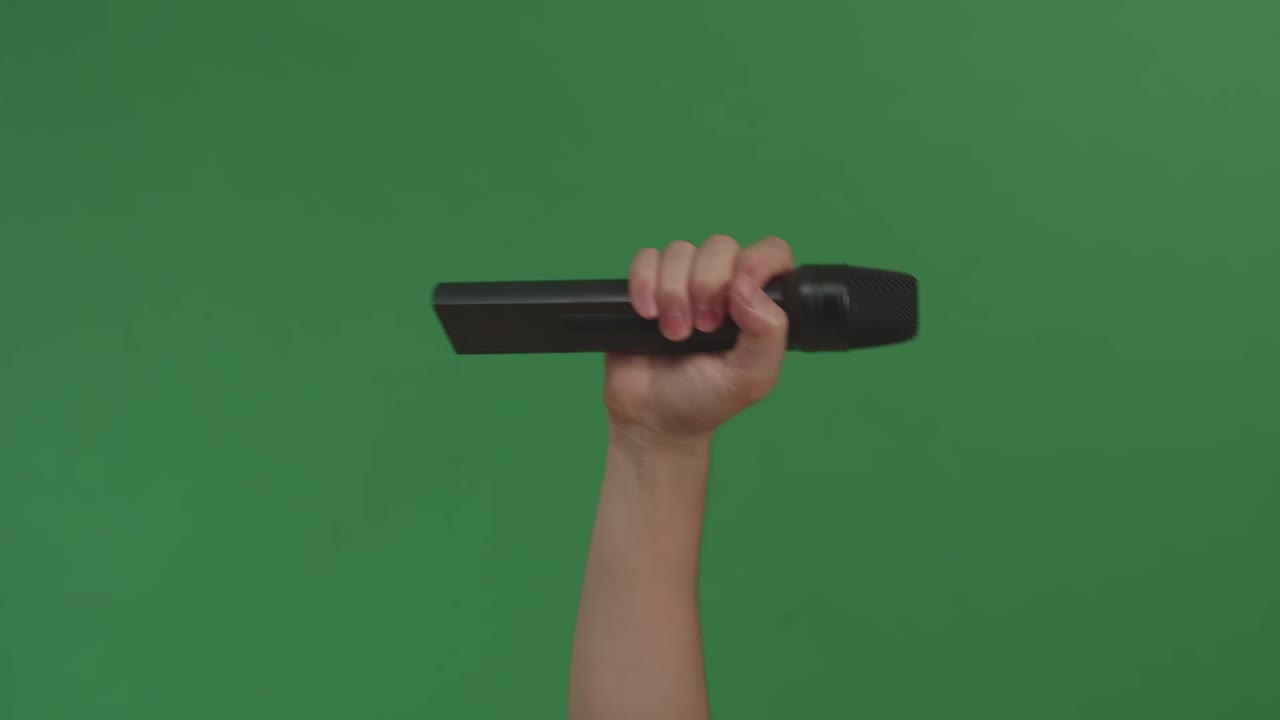 Male Hand Holding Microphone Against Background Green Screen Chroma Key. Close Up Mic, Live Press Conference, Karaoke, Singer Performance