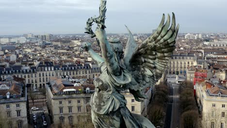 Close-up-of-Liberty-Angel-Girondins-monument-in-Bordeaux,-France,-with-city-panorama-and-Garonne-river,-Aerial-orbit-reveal-shot