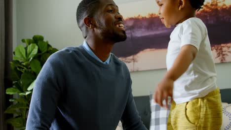 vista lateral de un joven padre y hijo negros jugando en la sala de estar de una casa cómoda 4k