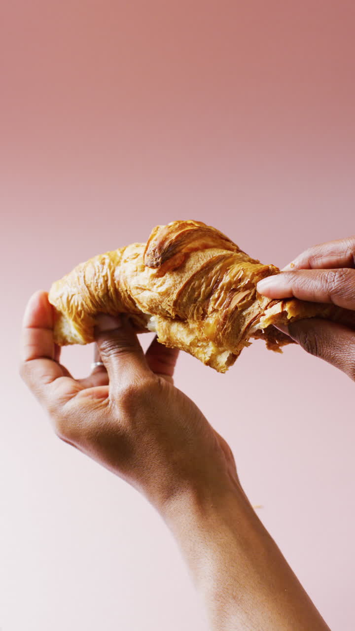 Video verticale di primo piano di mani che tengono un cornetto su sfondo grigio