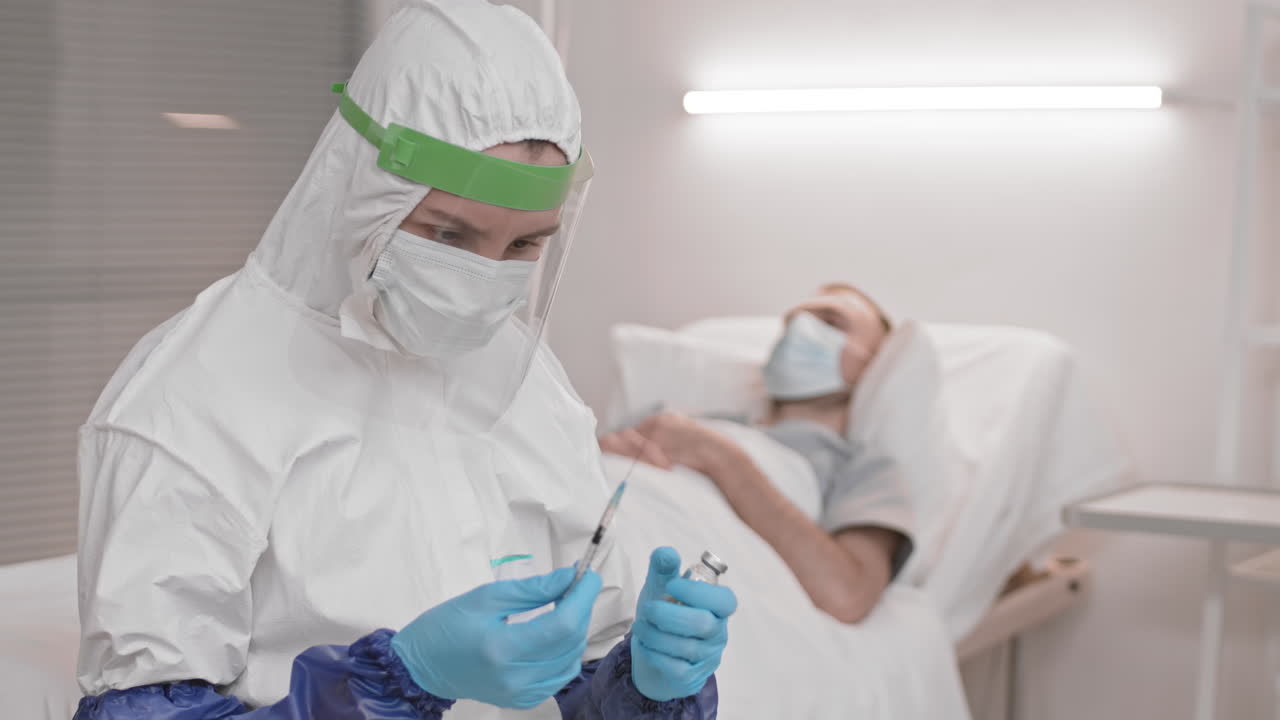 의사가 환자 방에서 주사기를 채우고 있습니다.