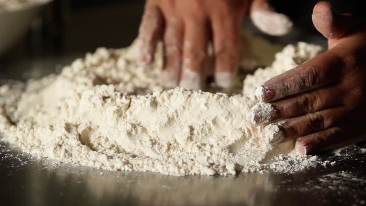 female hands mixing powder with water and eggs for pizza dough