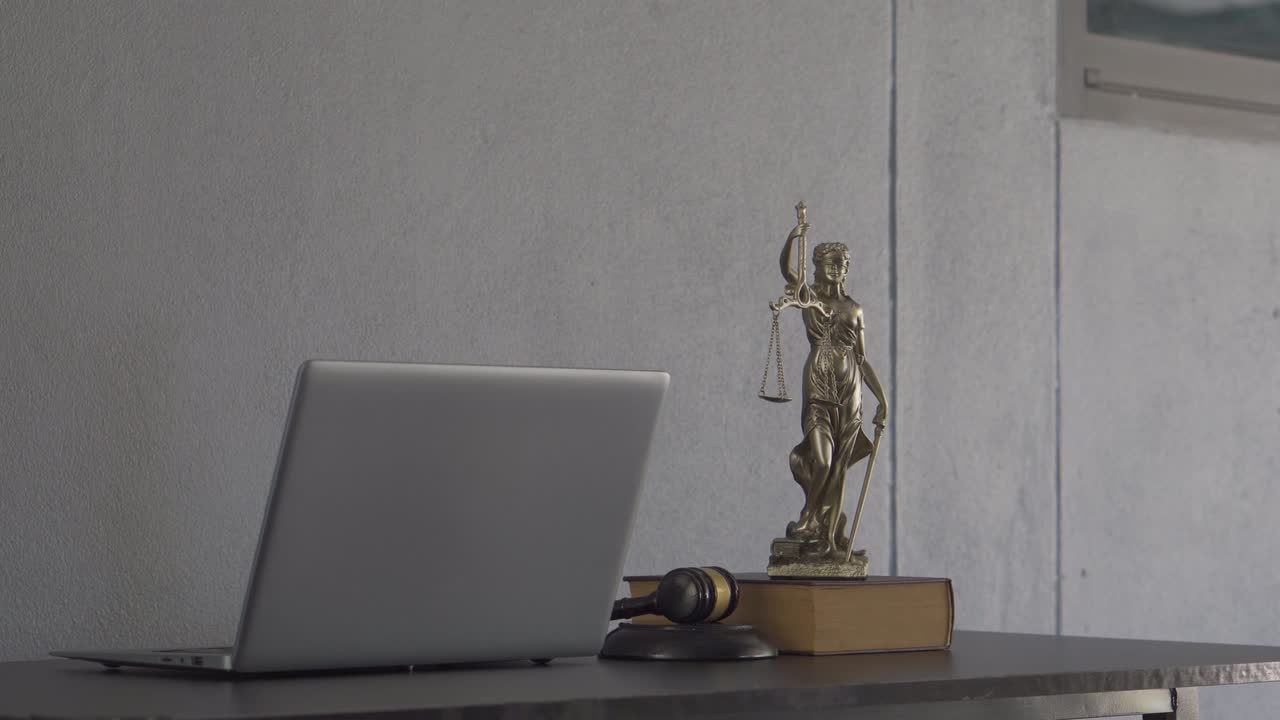 Laptop, martello del giudice, libri e bilancia. La dea della giustizia sul tavolo del concetto di consulenza legale.
