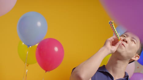 파티 모자를 입은 남자의 스튜디오 초상화, 풍선과 파티 불꽃으로 생일을 축하합니다.