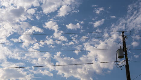 fluffy clouds float by over the power lines - time lapse cloudscape