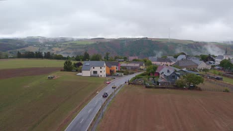 Cars-driving-towards-Bourscheid-at-Luxembourg-during-a-moody-day,-aerial