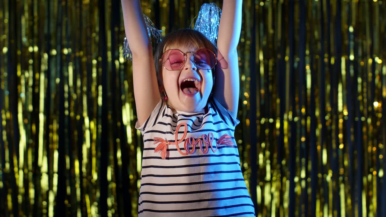 귀여운 작은 소녀는 성공을 즐기고, 승리를 축하하고, 승리를 기하며, 나이트 클럽에서 동기를 부여받습니다.