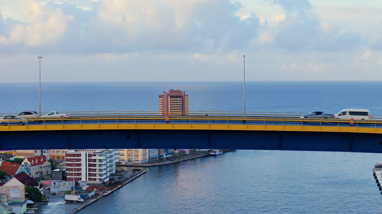 el dron se eleva para revelar los emblemáticos edificios coloridos de willemstad curaçao pasando el tráfico conduciendo en el puente