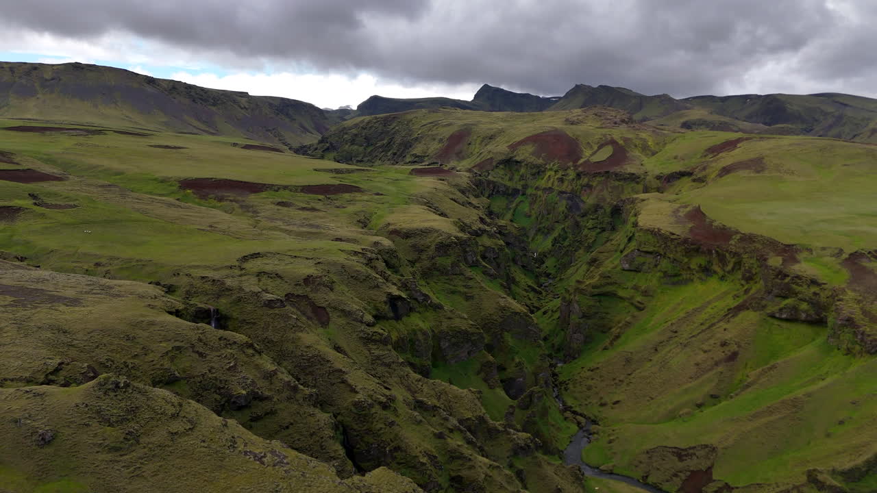 Vista aerea da drone del suggestivo canyon di Mýrdalshreppur con profonde gole vulcaniche, scogliere coperte di muschio e un fiume tortuoso che attraversa le vivide terre alte verdi nell'Islanda meridionale
