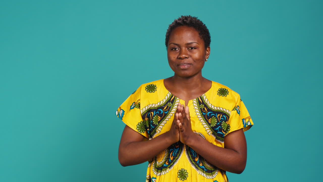 Optimistic woman praying to receive something in studio