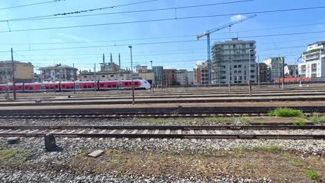 red train moving through milan railway tracks