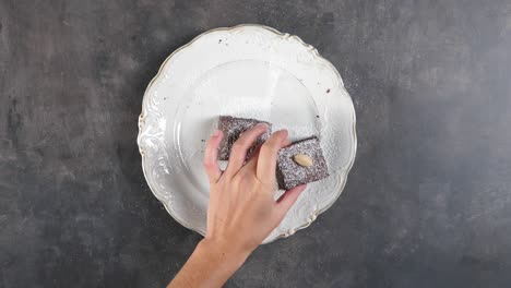 Top-down-shot-of-human-caucasian-hands-taking-pieces-of-chocolate-cake-off-the-white-plate