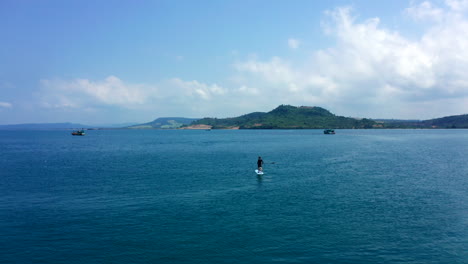 Aerial-drone-footage-flying-over-the-sea-showing-a-toursit-with-his-dog-on-a-paddle-board-in-Cambodia